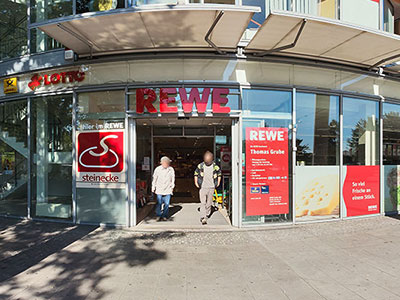 Zwei Menschen verlassen den REWE Markt